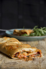 Stromboli on black background, wood surface plate