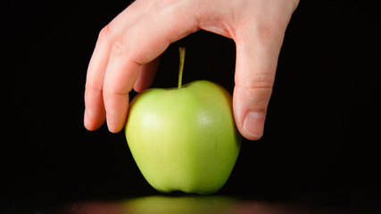 Human hand takes a green apple