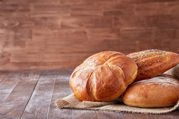 Fresh hot bread in a linen towel on a brown wooden table. free space for writing text. menu. advertising