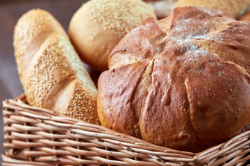 Different white bread in the wicker basket on the brown background. Close-up.