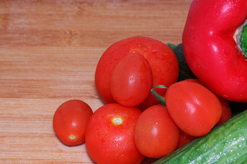 Paprika, tomatoes, cucumber fresh and washed on a wooden board