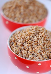 Buckwheat porridge  in a red bowl in polka dots On a light backgroun. breakfast