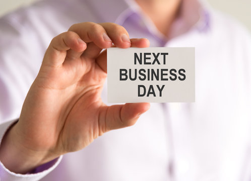 Businessman holding a card with NEXT BUSINESS DAY message