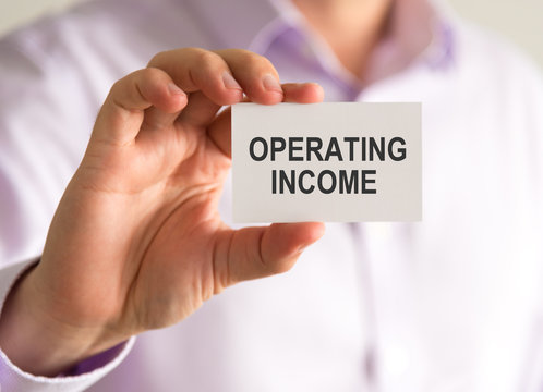 Businessman holding a card with OPERATING INCOME message