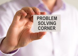 Businessman holding a card with PROBLEM SOLVING CORNER message