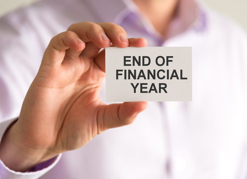 Businessman holding a card with END OF FINANCIAL YEAR message