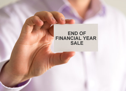 Businessman holding a card with END OF FINANCIAL YEAR SALE message