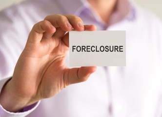 Businessman holding a card with FORECLOSURE message