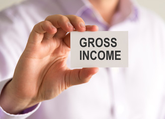 Businessman holding a card with GROSS INCOME message