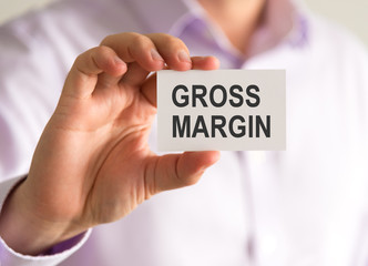 Businessman holding a card with GROSS MARGIN message