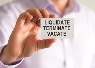 Businessman holding a card with LIQUIDATE, TERMINATE, VACATE message