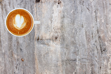 Top view of a coffee with heart pattern in a white cup on wooden background