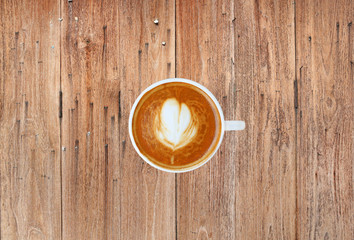 Top view of a coffee with heart pattern in a white cup on wooden background, latte art