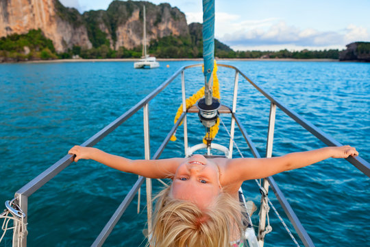 Joyful child portrait. Happy little baby girl on board of sailing yacht have fun discovering islands in tropical sea on summer coastal cruise. Travel adventure, yachting with kids on family vacation.