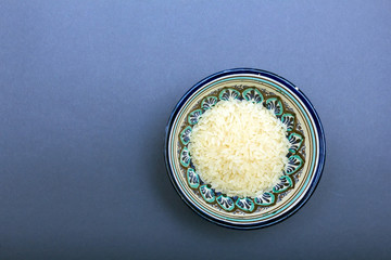 Rice in a colored clay bowl on gray background