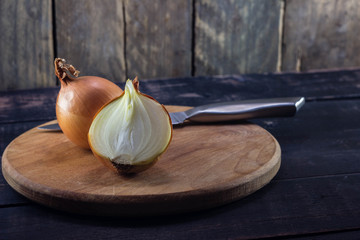 Ripe sliced onion with knife on rustic wooden background