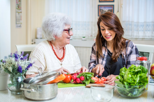 Grandmother and her granddaughter preparing healthy food together in the kitchen.