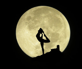 silhouette of a young man practicing yoga with the full moon on the background