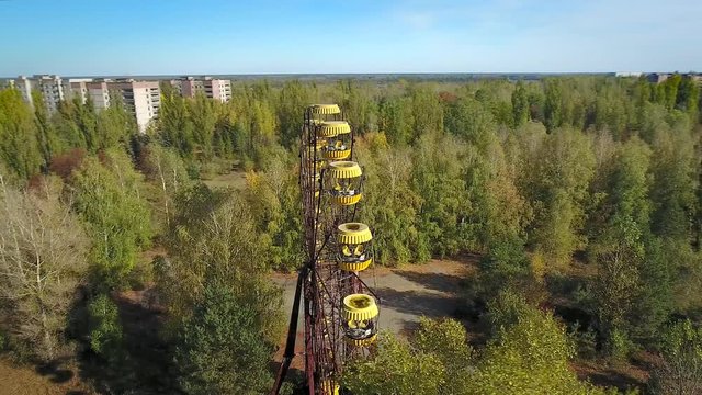 Panning orbit around abandoned ferris wheel of Pripyat Town after meltdown of Chernobyl nuclear power plant in 1986. Reactor & new sarcophagus are seen on the horizon. Oct 2016.