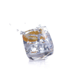 orange splashing into glass of water on white background