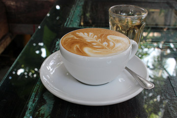 Hot Latte on Wooden Glass-Topped Coffee Table Outside