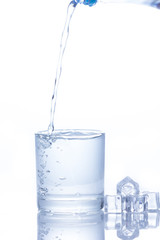 Water is poured into a glass with ice cubes