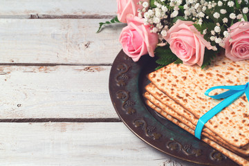 Jewish holiday Passover Pesah celebration with  matzoh and rose flowers over wooden background with copy space