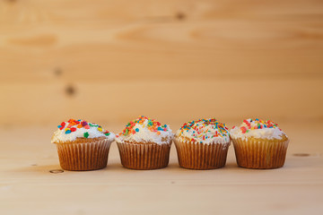Easter cupcakes with cream and small confetti on a wooden table. Spring.