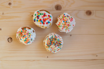 Easter cupcakes with cream and small confetti on a wooden table. Spring.