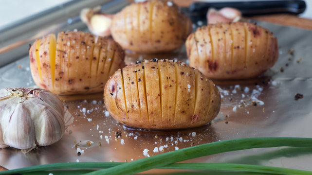 sliced raw potatoes with spice on foil for baking