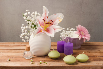 Spa and wellness concept with flowers in vase and candles on wooden table over rustic background