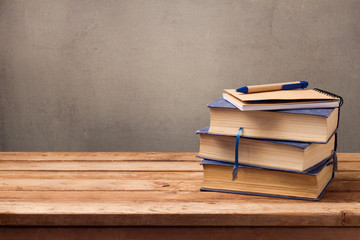 Vintage books and notebook on wooden table over rustic background