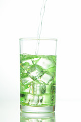 Water is poured into a glass with ice cubes
