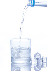 Water is poured into a glass with ice cubes
