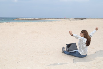 ビーチの若い女性とノートパソコン
