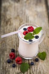 Smoothies or yogurt with fresh berries on a wooden table.