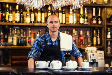 Barman at work in pub,Portrait of cheerful barman worker standing,Waiter giving menus,A pub.Bar.Restaurant.Classic.Evening.European restaurant.European bar.American restaurant.American bar.