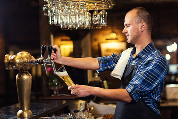 Bartender pouring the fresh beer in pub,barman hand at beer tap pouring a draught lager beer,beer from the tap,Filling glass with beer,fresh beer,pub.Bar.Restaurant.European bar.American bar.