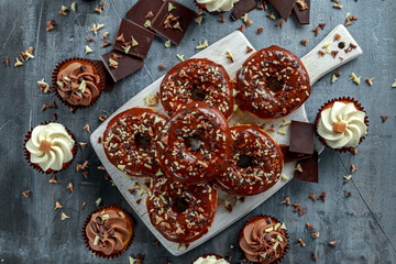 donut rings and vanilla caramel cupcakes with white and dark chocolate chippings and icing served on board