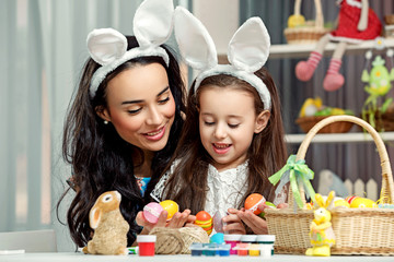 Happy easter! A mother and her daughter. Happy family preparing for Easter. Cute little child girl and mom wearing bunny ears on Easter day.