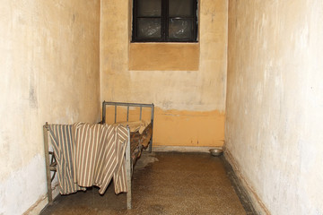 an old prison cell with a bed frame and footlocker