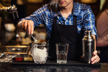 Barman at work,Barman pouring hard spirit into glasses in detail,Bartender is pouring tequila into glass,preparing cocktails,concept about service and beverages
