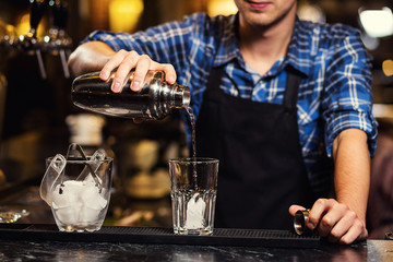 Barman at work,Barman pouring hard spirit into glasses in detail,Bartender is pouring tequila into glass,preparing cocktails,concept about service and beverages