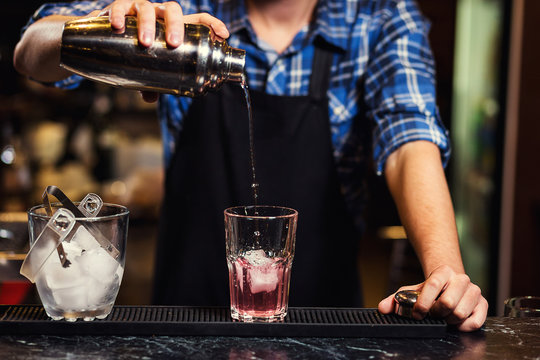 Barman at work,Barman pouring hard spirit into glasses in detail,Bartender is pouring tequila into glass,preparing cocktails,concept about service and beverages