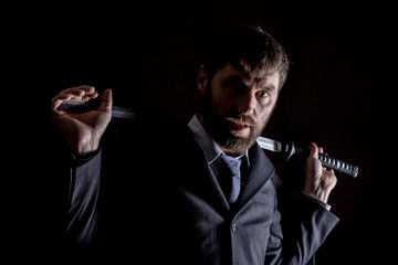 stern angry businessman in a wool coat with sword in dark background
