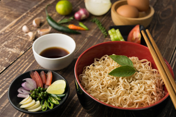 Noodles with sauce or shoyu and ingredient on table wood backgroound in close up.
