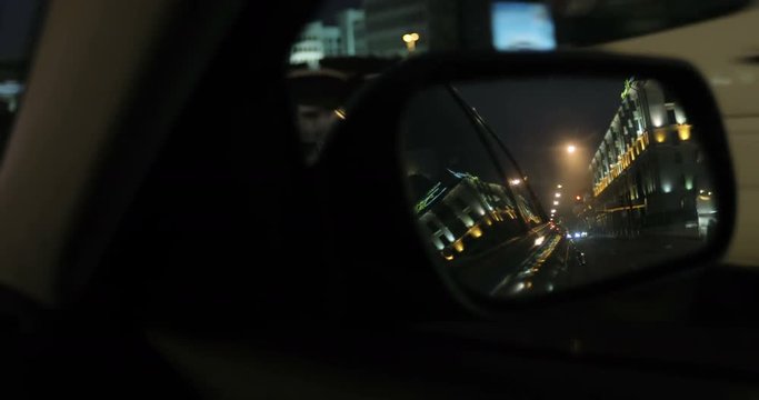 The view from the side mirror of the car. Night city.