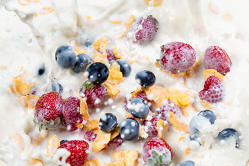 splash corn flakes with fresh berries and pouring milk.