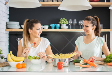Twin sisters preparing healthy food in the kitchen.