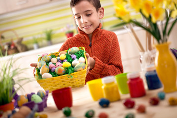 Naklejka premium Happy boy holding colorfull Easter basket